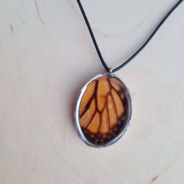 Real cruelty free, ethically harvested monarch buttery wing pendant in a oval shaped open backed silver bezel on coated cotton cord