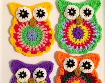 May include: Four colorful, handmade crochet owl ornaments. Each owl features large white eyes with black centers and a decorative, multi-colored body. The owls are in shades of yellow, green, purple, and orange.