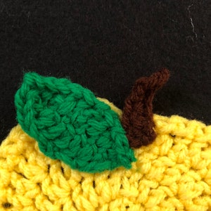 Puede incluir: Un lim&oacute;n de crochet con una hoja verde y un tallo marr&oacute;n. El lim&oacute;n es amarillo y la hoja es verde. El tallo es marr&oacute;n.