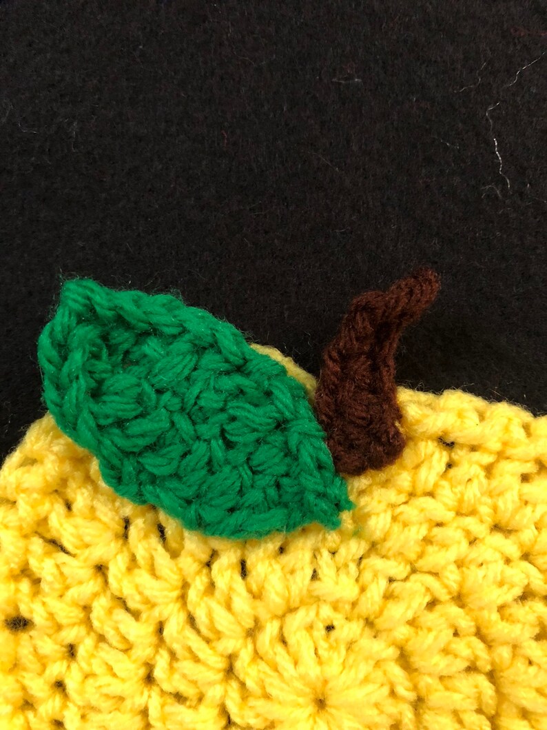Puede incluir: Un lim&oacute;n de crochet con una hoja verde y un tallo marr&oacute;n. El lim&oacute;n es amarillo y la hoja es verde. El tallo es marr&oacute;n.