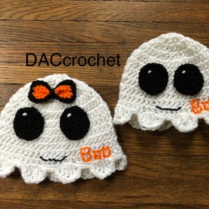 May include: Two crocheted ghost hats, one with an orange bow and the other with the word "Boo" embroidered on it. Both hats have black eyes and a white crocheted face.
