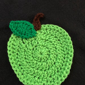 Puede incluir: Una manzana de ganchillo verde con un tallo marr&oacute;n y una hoja verde.
