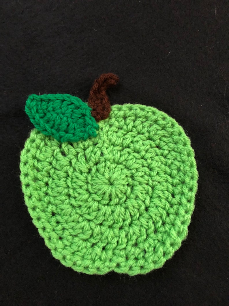 Puede incluir: Una manzana de ganchillo verde con un tallo marr&oacute;n y una hoja verde.