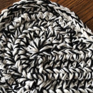 May include: Close-up of a black and white crocheted fabric with a textured pattern.