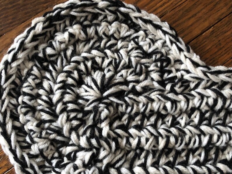 May include: Close-up of a black and white crocheted fabric with a textured pattern.