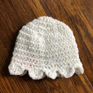 May include: White crocheted hat with a scalloped edge.