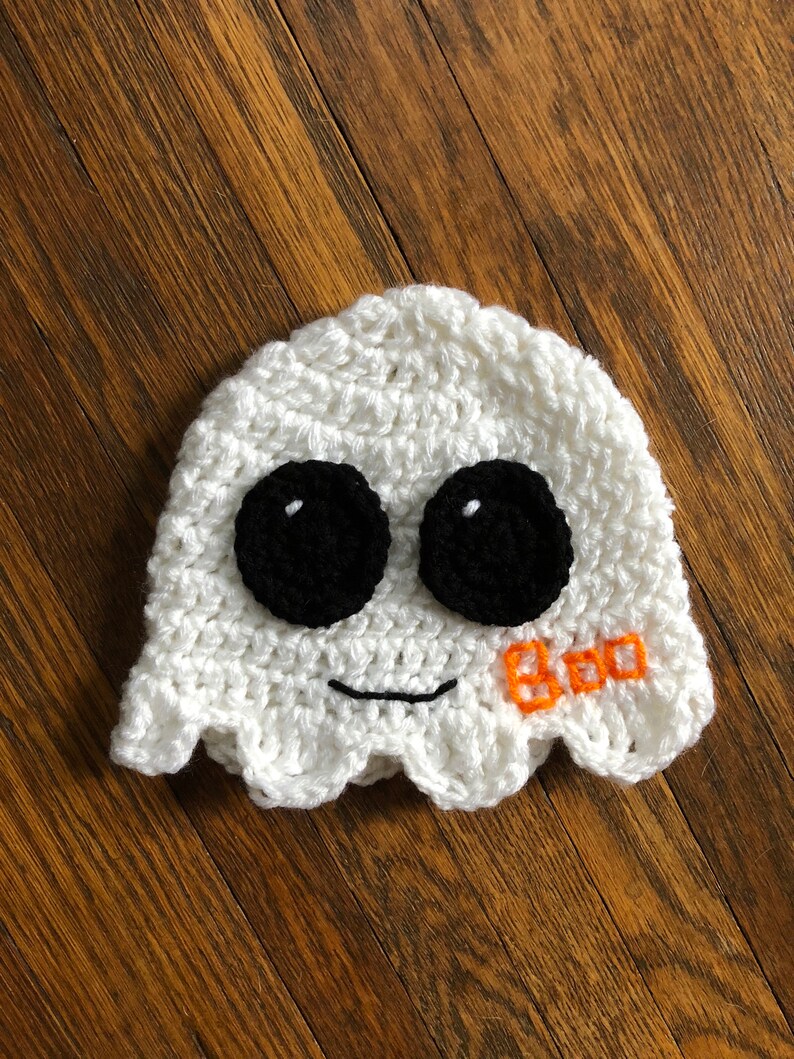 May include: White crocheted ghost hat with black eyes and a stitched orange "BOO" on the side.