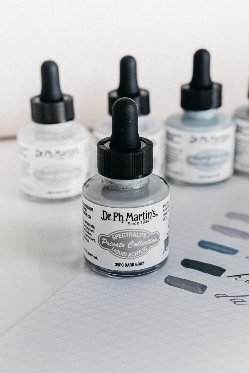 May include: A white ceramic mug with a black handle and the text "But First, Coffee" in a black, handwritten-style font. The mug is on a white surface.