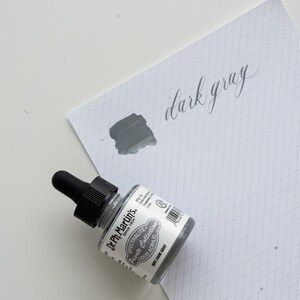 May include: A set of three ceramic mugs with a speckled, matte finish. The mugs are in shades of cream, light gray, and dark gray. Each mug has a simple, minimalist design and a rounded handle. Perfect for coffee or tea.