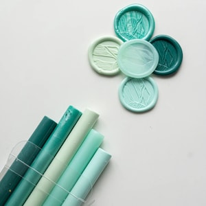 May include: Assortment of five teal and green wax seals with a stack of five teal, green, and blue wax sticks.