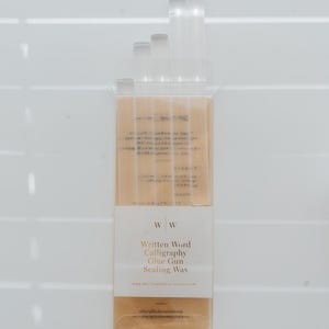 A pack of sealing wax sticks for a glue gun. The clear packaging has a white label with the text "Written Word Calligraphy Glue Gun Sealing Wax." The wax sticks are a clear.