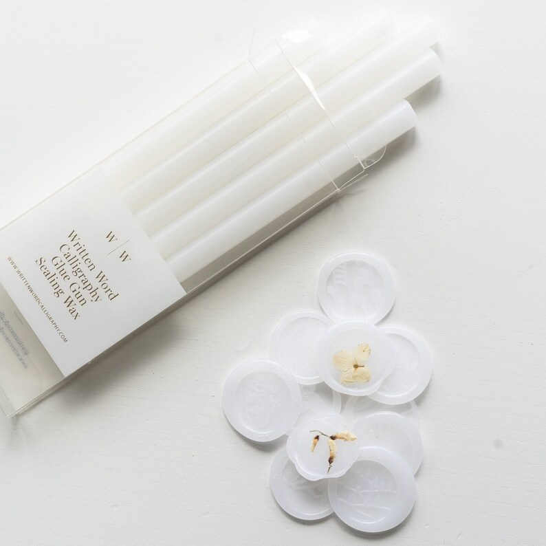 A pack of vellum glue gun sealing wax sticks with the text "Written Word Calligraphy Glue Gun Sealing Wax" on the front. There are also several vellum wax seals with dried flowers inside.