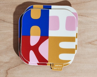 Könnte beinhalten: Ein quadratischer Aufkleber mit einem farbenfrohen Design. Das Design ist in vier Bereiche unterteilt: Blau, Rosa, Weiß und Gold. Die Buchstaben "H" und "K" sind sichtbar. Der Aufkleber hat eine kleine Lasche mit der Aufschrift "peel here".