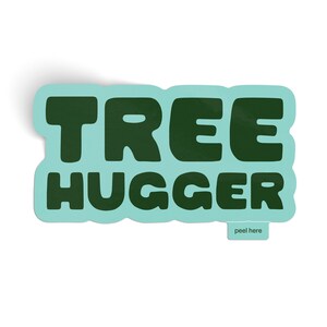 May include: A teal blue sticker with the text "TREE HUGGER" in dark green letters. The sticker has a peel-off backing with the text "peel here" printed on it.