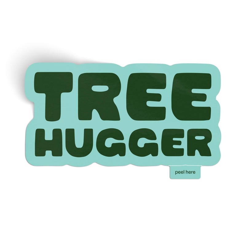 May include: A teal blue sticker with the text "TREE HUGGER" in dark green letters. The sticker has a peel-off backing with the text "peel here" printed on it.