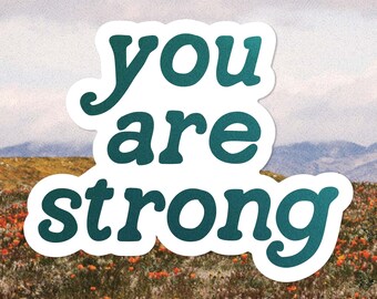 May include: A white sticker with a teal blue message that reads "you are strong" against a backdrop of a field of flowers.