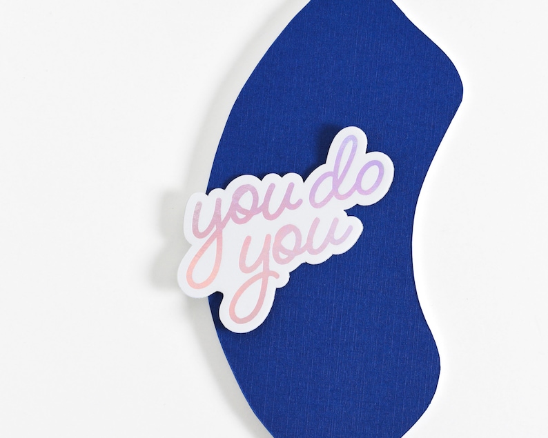 May include: A white sticker with the text "you do you" in a pink and purple gradient on a blue background.