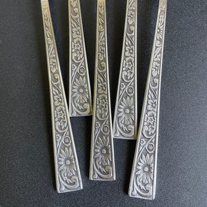 May include: Five silver forks with floral designs on the handles.