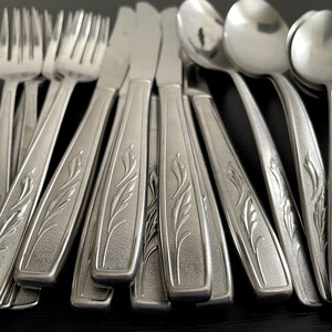May include: A set of stainless steel silverware with an ornate floral design. The silverware includes forks, knives, and spoons.