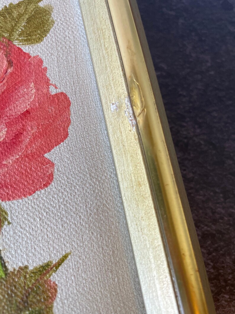 May include: Close-up of a framed floral painting. The artwork features a large red rose with green leaves against a light background. The frame is gold-colored metal and light wood. The painting is a close-up of the rose.