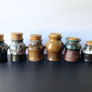 May include: A set of three ceramic mugs with a speckled, matte finish. The mugs are in shades of cream, light gray, and dark gray. Each mug has a simple, minimalist design, perfect for coffee or tea.