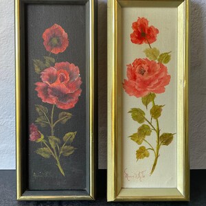 May include: Two framed floral paintings. One features a red rose on a black background, the other a red rose on a cream background. Both are in rectangular gold frames. The artist's signature, "Marie White", is visible on both.