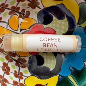 May include: A white tube of lip butter with the words "Coffee Bean Lip Butter" printed on the label.