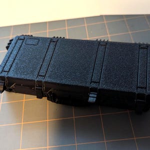 May include: A black hard-sided case with latches and a handle. The case has a textured surface.