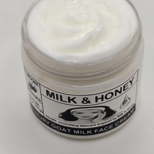 Puede incluir: Un tarro de crema facial blanca con la inscripci&oacute;n "Milk & Honey" en la etiqueta. La crema tiene una textura suave y arremolinada. La etiqueta tambi&eacute;n dice "Luxury Goat Milk Face Cream".
