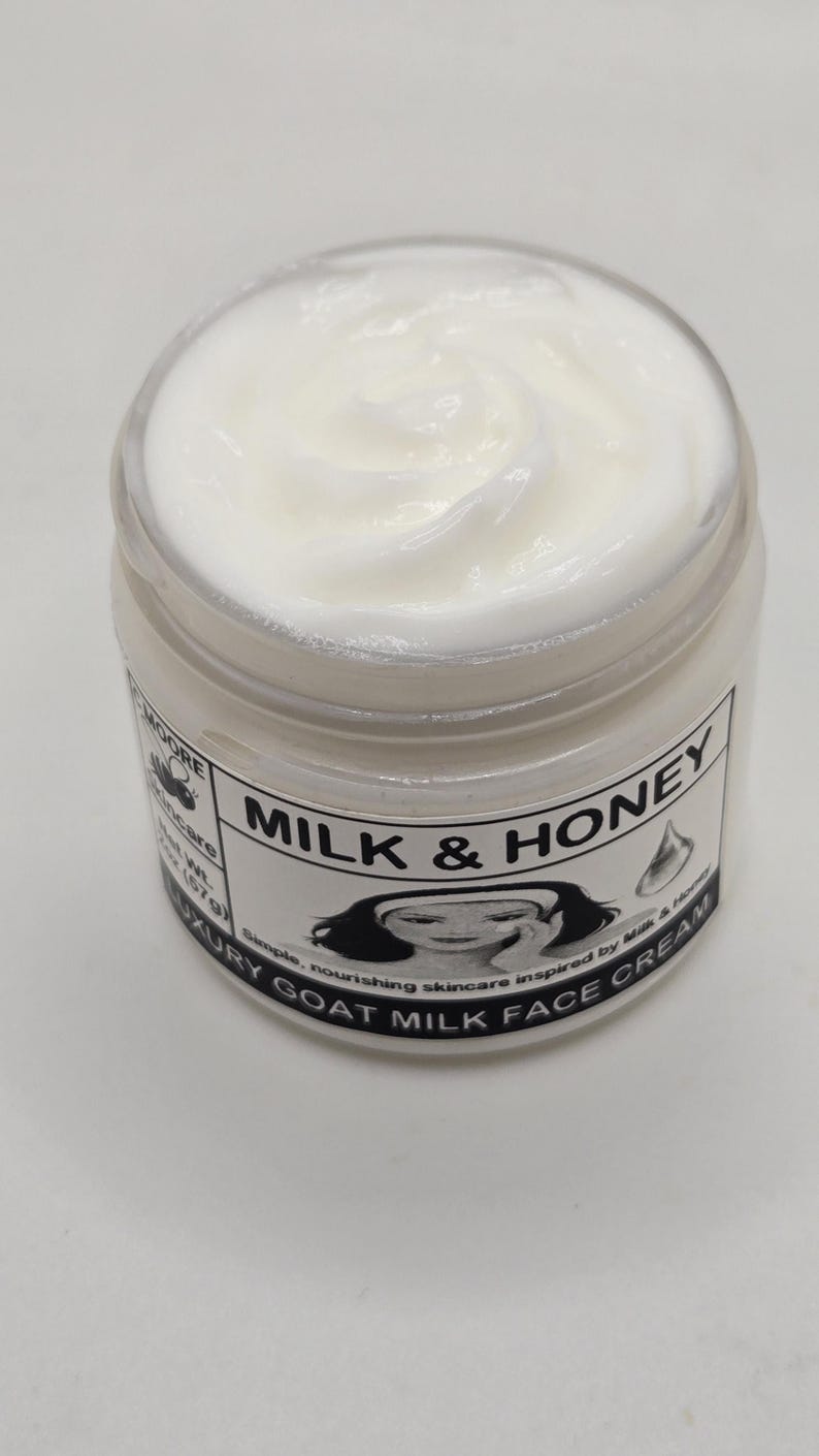 Puede incluir: Un tarro de crema facial blanca con la inscripci&oacute;n "Milk & Honey" en la etiqueta. La crema tiene una textura suave y arremolinada. La etiqueta tambi&eacute;n dice "Luxury Goat Milk Face Cream".