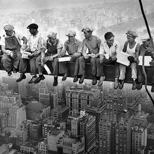 May include: A black and white photograph of eleven construction workers sitting on a steel beam high above the city. The workers are eating lunch and looking out at the cityscape. The photo is a classic example of the dangers and challenges of construction work.