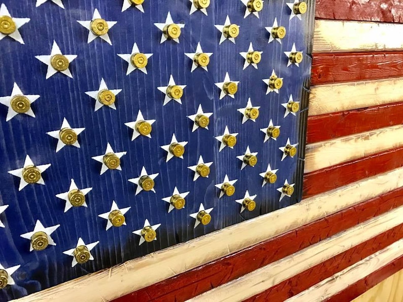 Op de afbeelding: Een Amerikaanse houten vlag met rode, witte en blauwe strepen. De sterren zijn gemaakt van gouden kogelhulzen.