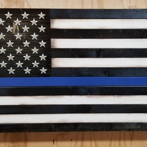 May include: A wooden American flag with a blue line, representing support for law enforcement. The flag is distressed and has a rustic look.