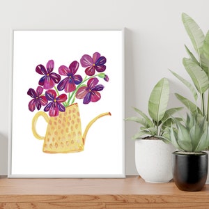 Puede incluir: Una regadera amarilla con estampado de lunares llena de flores moradas. La regadera tiene un pico y un asa. Las flores est&aacute;n dispuestas en un ramo.