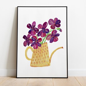 Puede incluir: Una regadera amarilla con estampado de lunares llena de un ramo de flores moradas.