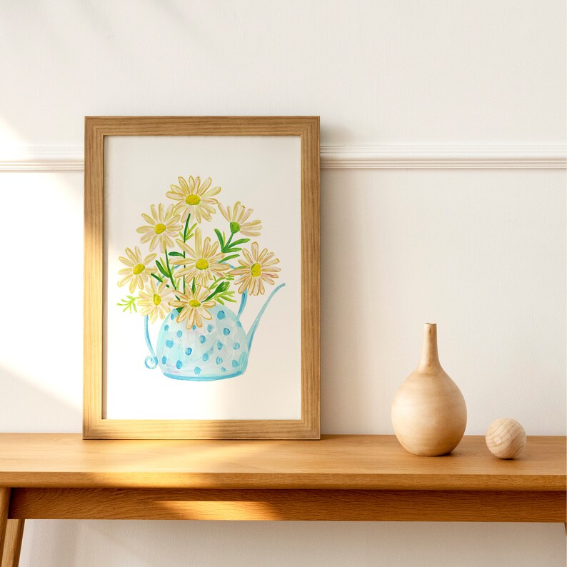 May include: A framed watercolor painting of a blue teapot with white polka dots filled with yellow daisies.