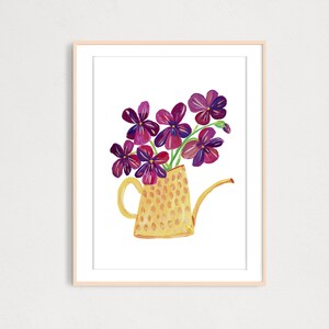Puede incluir: Una regadera amarilla con estampado de lunares llena de un ramo de flores moradas.