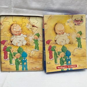 May include: A vintage 20-piece puzzle featuring a baby in a crib surrounded by fairies. The puzzle box is red and white with the title "Baby's Care" and the brand "Waddingtons".