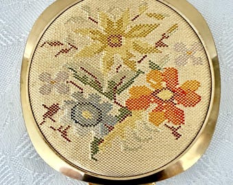 Polvos compactos "Pink Lady" de los años 60, sin usar, en tono dorado, bordados en seda, con tamizador original y borla con monograma. Fabricados en Japón.