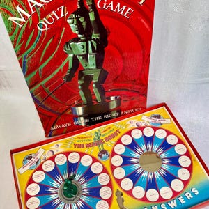 May include: A Merit Magic Robot Quiz Game featuring a red box with a green robot illustration and the text "Always gives the right answer." The game board includes two circular sections with white question and answer circles and a green robot figure.