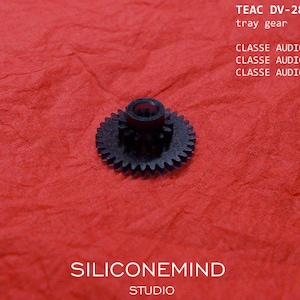 Puede incluir: Un engranaje de bandeja negro para TEAC DV-28SL, con el texto "TEAC DV-28SL tray gear" y "CLASSE AUDIO CDP202 CLASSE AUDIO CDP300 CLASSE AUDIO CDP502". El engranaje está sobre un fondo rojo, con el texto "SILICONEMIND STUDIO".