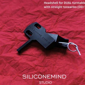 Può includere: Testina nera per giradischi DUAL con bracci dritti. La testina è realizzata in plastica e presenta la scritta "SILICONEMIND STUDIO" stampata su di essa. La testina è progettata per bracci con un diametro esterno di 7-7,1 mm.