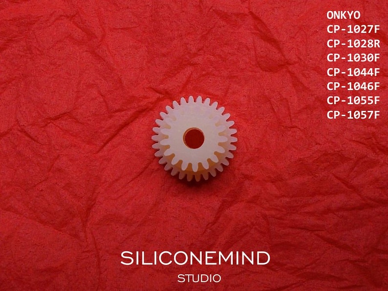 May include: A white plastic gear with a red center, on a red textured background. The text "SILICONEMIND STUDIO" and "ONKYO" with a list of model numbers is visible above the gear.