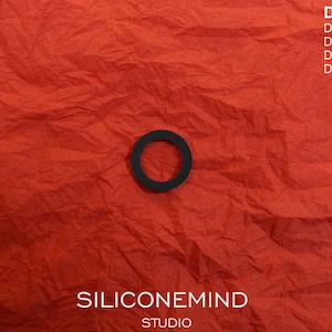 May include: A black rubber ring on a red crumpled paper background. The text "SILICONEMIND STUDIO" and "DENON DR-M11 DR-M22 DR-M33 DR-M44" is printed below the ring.