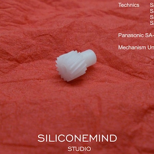 May include: A small, white plastic gear with a cylindrical post, set against a textured red background. The image includes text indicating compatibility with Technics and Panasonic audio equipment models, including SJ-MD100, SJ-MD150, and SA-PM35MD.