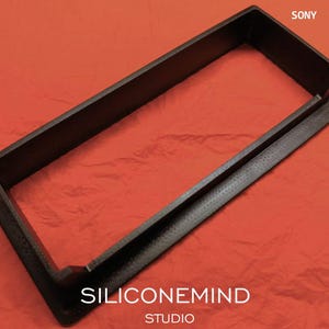 K&ouml;nnte beinhalten: Ein schwarzer rechteckiger Rahmen mit strukturierter Oberfl&auml;che, der einen erh&ouml;hten Innenrand und einen flachen Au&szlig;enflansch mit Schraubl&ouml;chern aufweist. Der Text SONY TC-630 TC-630D steht oben rechts und SILICONEMIND STUDIO unten.