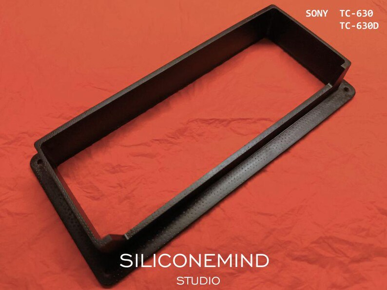 K&ouml;nnte beinhalten: Ein schwarzer rechteckiger Rahmen mit strukturierter Oberfl&auml;che, der einen erh&ouml;hten Innenrand und einen flachen Au&szlig;enflansch mit Schraubl&ouml;chern aufweist. Der Text SONY TC-630 TC-630D steht oben rechts und SILICONEMIND STUDIO unten.