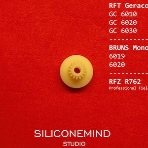 Könnte beinhalten: Ein kleines, blassgelbes Kunststoffzahnrad mit einem Mittelloch und radialen Zähnen. Der Text RFT Geracord GC 6010, GC 6020, GC 6030, BRUNS Monocord 6019, 6020, RFZ R762 Professional Field Recorder und SILICONEMIND STUDIO ist in Weiß gedruckt.
