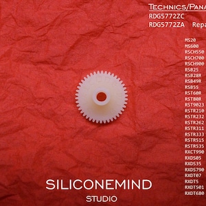 Peut inclure: Une pièce de rechange en plastique blanc avec un trou central, sur un fond rouge texturé. L'image comprend du texte indiquant qu'elle est destinée aux modèles Technics/Panasonic, ainsi qu'une liste de numéros de modèles compatibles. Le nom du studio "SILICONEMIND" est également visible.