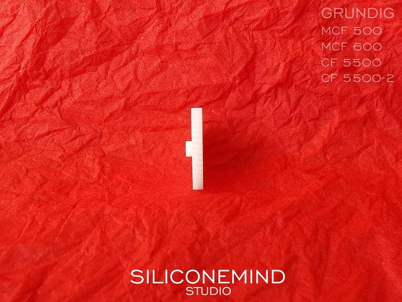 Puede incluir: Una perilla de pl&aacute;stico blanca con forma cuadrada y un peque&ntilde;o agujero en el centro. La perilla est&aacute; sobre un fondo rojo.